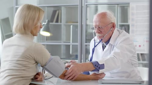 Doctor Checking Blood Pressure of Smiling Woman
