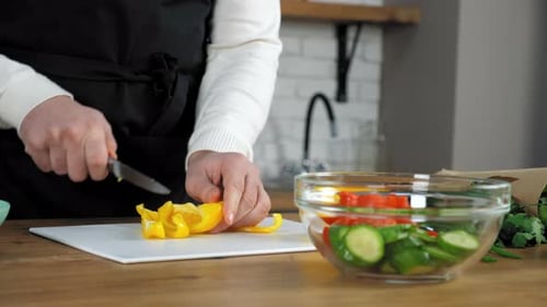 Woman Slicing Yellow Bell Pepper for Salad