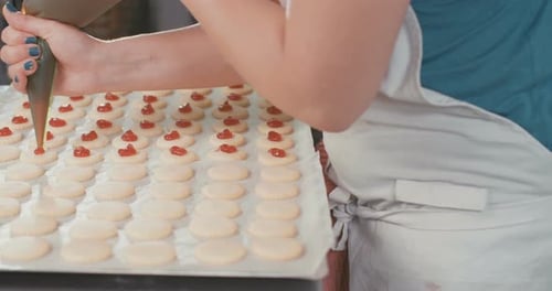 Baker preparing butter cookies with strawberry jam and powdered sugar