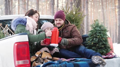 Family Enjoying Winter Beverage in Forest Truck Bed