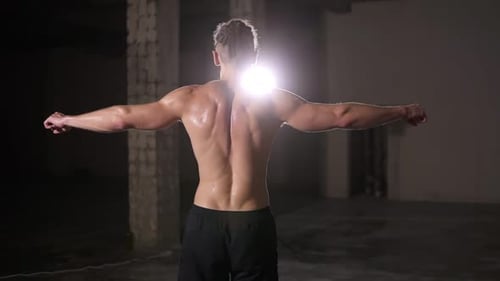Shirtless Muscular Man Standing in Dark Gym