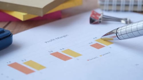 Mão de homem com caneta analisando gráfico de barras no papel