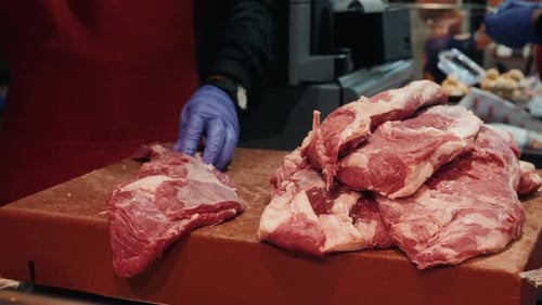 Hands with Knife of Smiling Butcher Cutting Meat at Counter in Butchery Pork Close Up