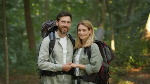Happy Loving Active Middle Aged Couple in Love with Backpack Hugging in Forest Enjoying Hiking Trip