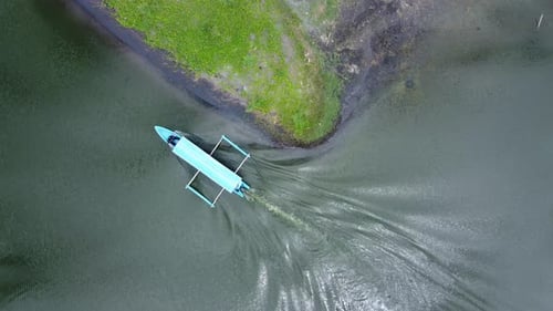 Imágenes aéreas de una lancha motora azul que viaja por un lago estrecho.