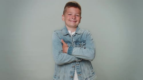Smiling Boy in Denim Jacket Crosses Arms