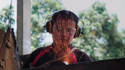 Man work in home workshop with angle grinder, goggles and construction gloves.