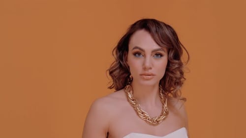 Glamorous Woman with Wavy Hair and Gold Necklace