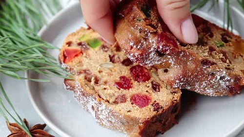 Woman lifts a piece of fruitcake from a plate