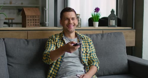 Cheerful Man Relaxing on Sofa with Remote