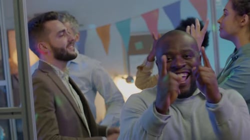 Retrato de funcionário animado dançando e olhando para a câmera curtindo a festa no escritório com colegas