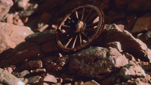 Old Wooden Wagon Wheel Resting on Rocky Ground