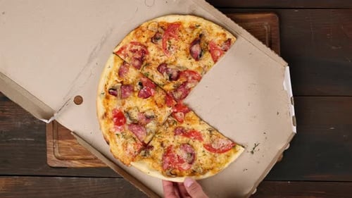 Hand Grabbing Slice of Pizza From Delivery Box