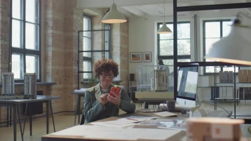 Female Architect Texting on Phone in Office