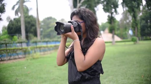 A tourist Asian girl takes photograph with a DSLR camera at a nature park