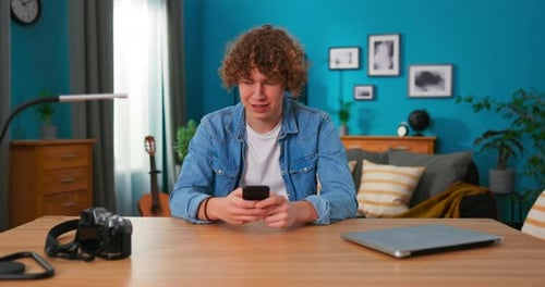 Teenage Man Using Smartphone Indoors at Desk
