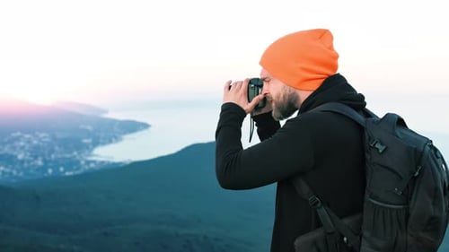 Medium Shot Hipster Male Professional Photographer on Mountain Taking Photo Sea Landscape