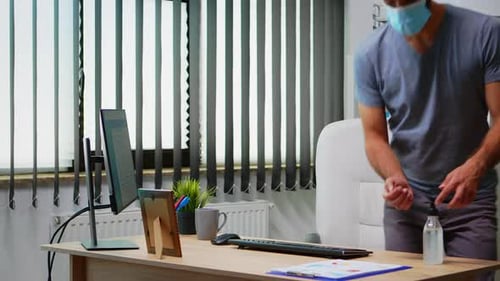 Man Sanitizing Hands Before Using Office Computer