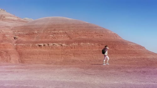 Filmmusik Glückliche, aufgeregte Frau, die am farbenfrohen Sandsteinhügel am blauen Himmel spaziert