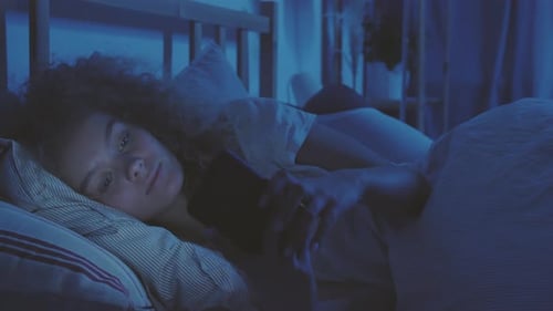Woman Using Mobile Phone Lying in Bed