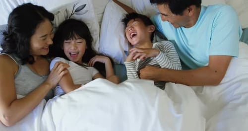 Family Laughing Together in Bed