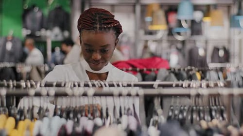 Young Stylish African American Girl Woman Shopper Consumer in Shopping Center Clothing Store Chooses
