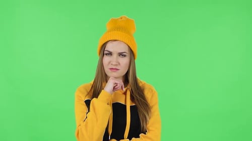 Portrait of Modern Girl in Yellow Hat Is Focused Thinking About Something, No Idea. Green Screen