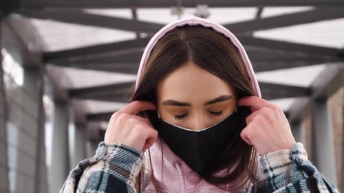 Young Woman Removing Mask in Urban Setting