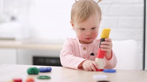 Blonde Child Playing with Stacking Toy at Table