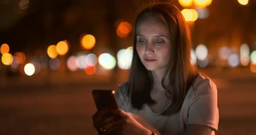 Woman Using Smartphone at Night in City