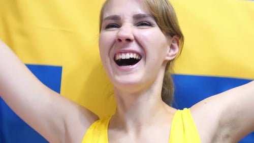 Smiling person in front of Swedish flag