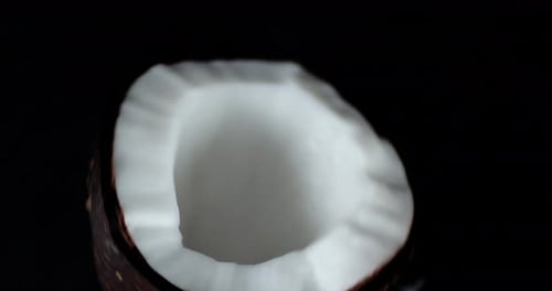 Rotating Half Coconut on Black Background Close Up
