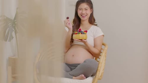 Pregnant Woman Eating Fruit in a Bright Room