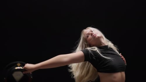 Alluring Young Woman Dancing in Studio Against Black Background