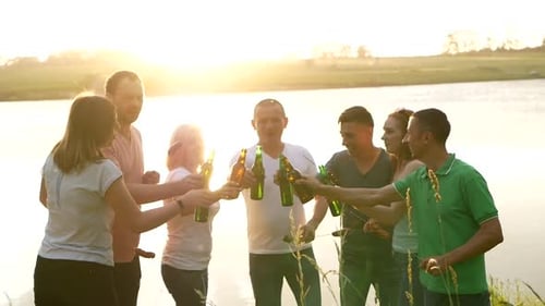 Amigos felizes dançando ao pôr do sol com uma bebida nas mãos