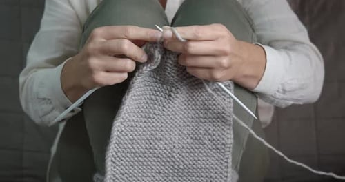 Woman Knitting Woolen Item While Sitting on Bed