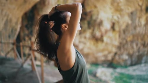 Femme en forme fixant ses cheveux avec les yeux fermés, appréciant les rayons du soleil