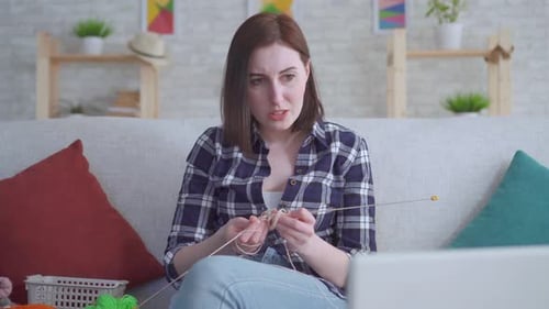 Woman Knitting and Looking Frustrated on Couch