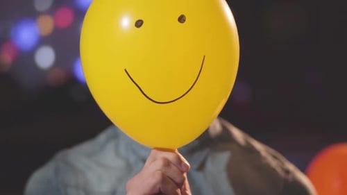 Smiling Teenager Holds Yellow Balloon With Smiley Face