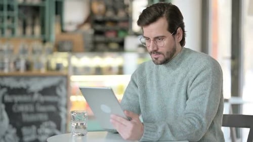 Young Man Using Tablet in Cafe