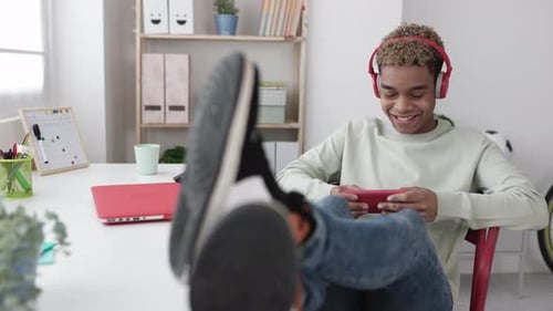 Joven adolescente latino adicto y sonriente jugando Vídeo en la aplicación de teléfono móvil