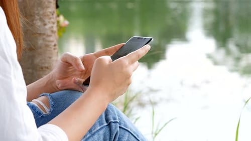 Close-up shot surfing the net online. Using mobile phones send text messaging at a public park.