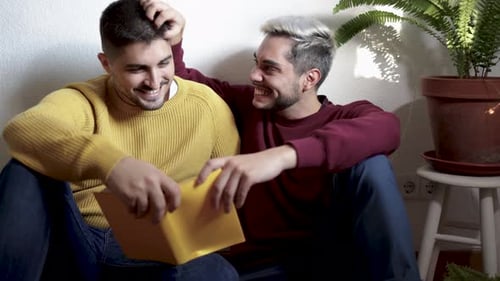Young Adults Laughing Together While Reading Book