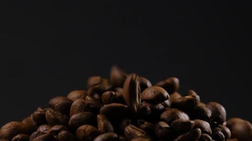 Zeitlupe fallender gerösteter Kaffeebohnen. Bio-Kaffeesamen.