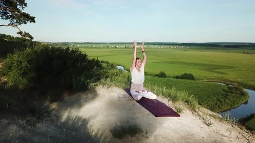 Aerial Shot View of Yogini Young Woman Sitting in Lotus Pose and Putting Up Hands in Namaste Mudra.