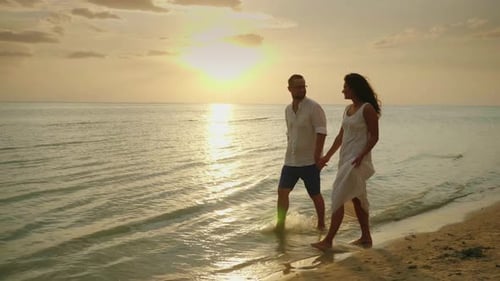 Romantic Couple in Love Walking By the Sea at Sunset