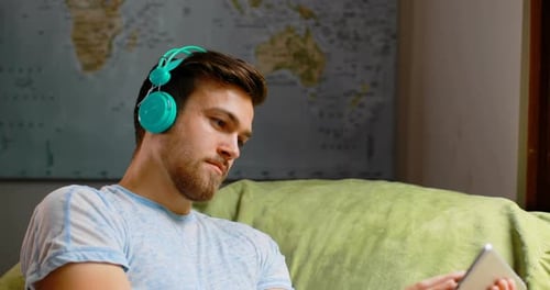 Man Uses Tablet with Blue Headphones
