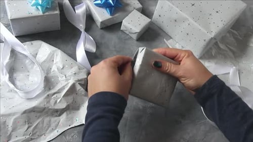 Hands Unwrapping Small Gift on Table Top