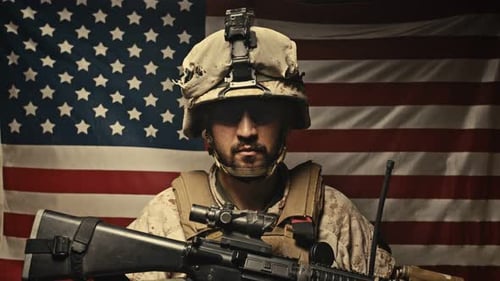 Serious Soldier Poses with Rifle in Front of Flag