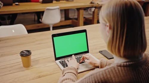 Over Shoulder View of Female Student Typing on Laptop with Green Chroma Key Screen Studying at